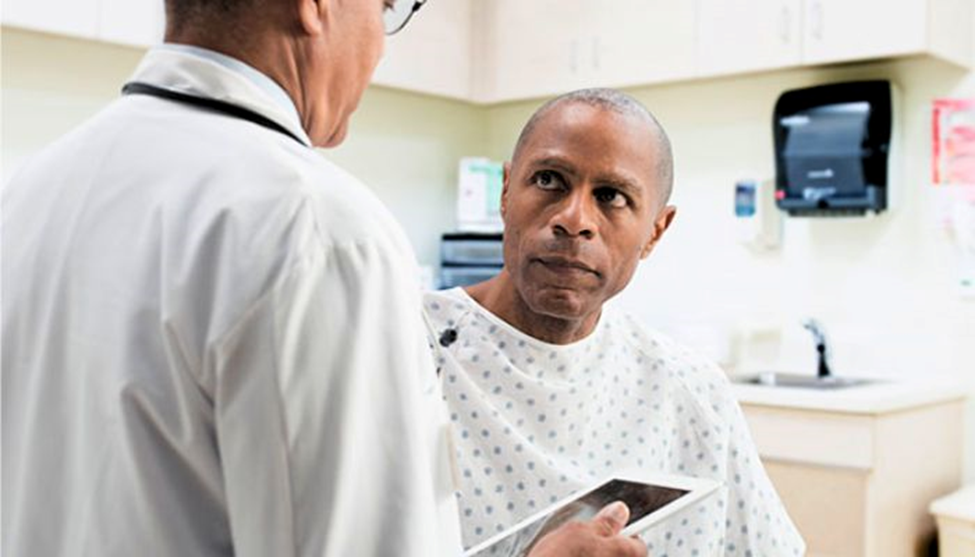 man in hospital, listening to doctor talking, the doctor is holding and ipad