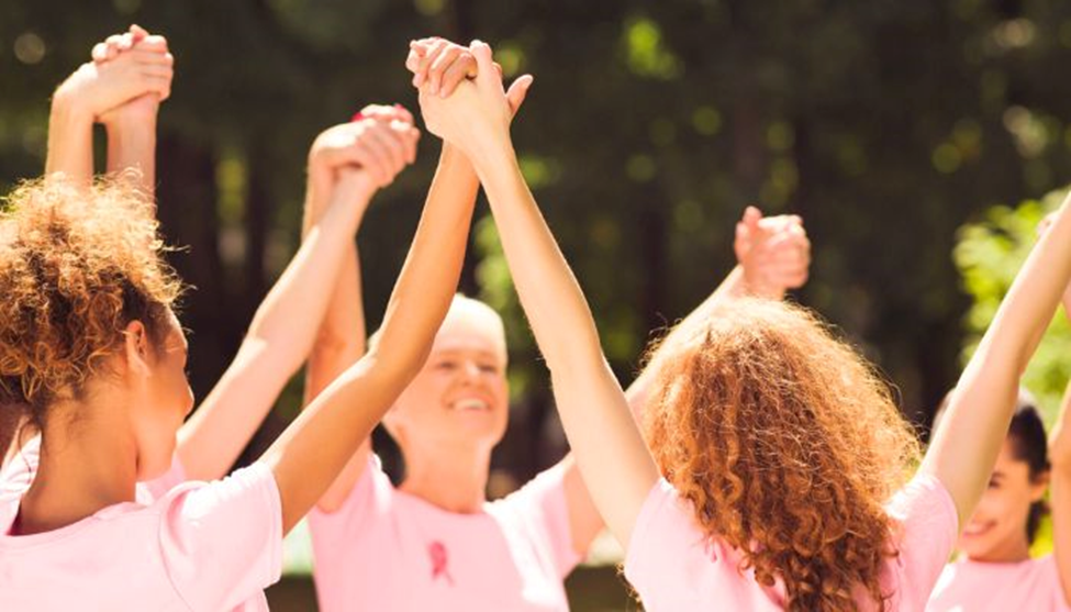 a group of women holding hands above their head wearing pink shirts